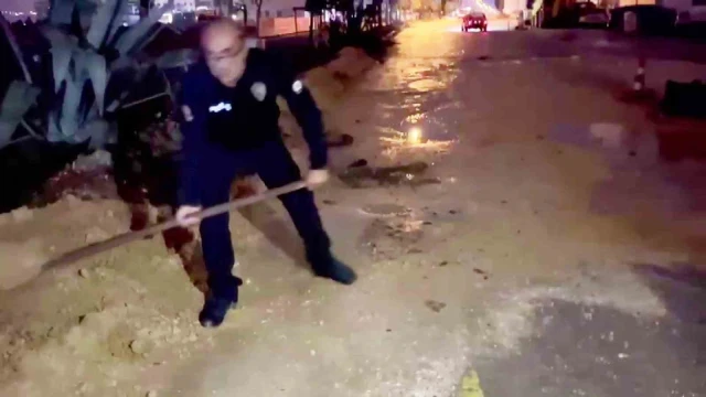 Araçlar zarar görmesin diye küreği eline alan polis memurları, suyla dolan çukurları toprakla doldurdular