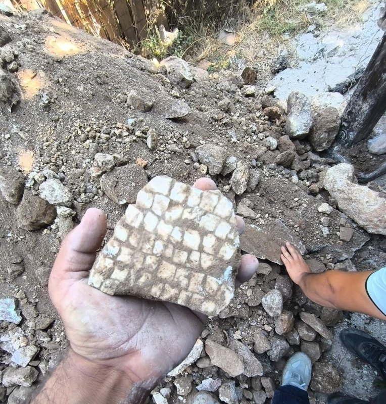 Alt yapı çalışmaları esnasında kepçeyle kazı yapılırken mozaik bulundu - Mahalle Sakini Yorgundağ, "Mahallemizde daha önce böyle bir olay yaşanmadı şaşırdık açıkçası" (Fotoğraflı) Ahmet Arslan HATAY (İHA) - Hatay'da ekiplerin kepçeyle yürüttüğü alt yapı çalışmaları esnasında bir bahçede mozaik buluntusu çıktı. Bölgede güvenlik önlemi alınırken, müze ekipleri eserin çıkartılmasıyla ilgili çalışma başlattı. Reyhanlı ilçesi Davutpaşa Mahallesi'nde alt yapı çalışmalarını sürdüren ekipler Yakup İmran'a ait bahçede yerin 1 buçuk metre altında kepçeyle kazı yaparken mozaik buluntusuna rastladılar. Durumun fark edilmesi üzerine ekipler konuyu jandarma ekiplerine bildirdiler. Jandarma bölgeye gelerek güvenlik önlemi alırken müze müdürlüğü ekipleri de tarihi eser olduğu belirlenen mozaiğin çıkartılması ve tarihinin belirlenmesi için çalışma başlattı. Bahçe sahibi Yakup İmran, geçmişte bahçesine ağaç diktiğini fakat herhangi bir buluntuya rastlamadığını söyledi. "Benim bahçemde kanalizasyon çalışması yapılırken mozaik çıktığını söylediler" Bahçe sahibi Yakup İmran, kazı çalışmaları esnasında mozaik çıktığını söyleyerek "Burası Davutpaşa Mahallesi. Benim bahçemde kanalizasyon çalışması yapılırken mozaik çıktığını söylediler. Tarihiyle ilgili bir bilgi yok. Daha önce de ben ektiğimde tarihi eserler çıktığını bilmiyordum, önem vermedim. Dut ve ağaç dikip, toprak doldurup üzerine gittim. Kazmayla 30 santim kazıp, ağaçları ektim. Devletimiz bilir her şeyin iyisini" dedi. "Mozaik çıktı ve çevresi örme duvar, tarihinin 1500 yıllık olduğu söyleniyor" Bölgede yürütülen çalışmalar esnasında örme duvarla çevrili alanda mozaik çıktığını ifade eden Abdullah Yorgundağ "Ekipler alt yapı çalışması için gelmişti. Evimizin yanında kazı yaptıkları esnada tarihi eser buldular. Jandarmayı aradılar ve bölgede güvenlik önlemi aldılar. Müze personeli arkadaşlar çalışmalara devam ediyorlar. İlk kez mahallemizde böyle bir tarihi eser çıktı. Mozaik çıktı ve çevresi örme duvar, tarihinin 1500 yıllık olduğu söyleniyor. Mahallemizde daha önce böyle bir olay yaşanmadı şaşırdık açıkçası" dedi.