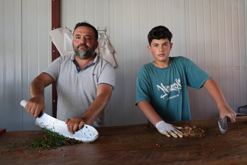 6 yıldır babasının yanında mesleği öğrenen 14 yaşındaki kasap, yılların ustalarına meydan okuyor (Fotoğraflı) Ramazan İlın HATAY (İHA) - Hatay'da yaşıtlarının aksine telefonla oyun oynamak yerine aile mesleği kasaplığını öğrenen 14 yaşındaki Muhammed Enes Başak, usta elleriyle eşsiz tatlara lezzet veriyor. Antakya ilçesi Esenlik Mahallesi'nde yaşayan 14 yaşındaki Muhammed Enes Başak, 8 yaşından beri kasaplık yapan babası Nuri Başak'ın yanında mesleğin inceliklerini öğreniyor. Babasına ait kasap dükkanında usanmadan, pes etmeden mesai yapan kasap Başak; babasından öğrendiği mesleğinde kendini geliştirmeye devam ediyor. İş yerine gelen müşterilerin özel istekte bulunduğu Muhammed Enes Usta; hayvan kesimi gerçekleştirirken Hatay’ın eşsiz lezzetleri olan kağıt kebabı, tepsi kebabı ve lahmacun gibi yemekleri yapabiliyor. Okul zamanlarında okula giden Muhammed Enes Usta, okul sonrası çoğu zamanını babasının yanında çalışarak geçiriyor. Ailede gelenek haline gelmiş kasaplık mesleğini devam ettiren Muhammed Enes Usta, ilerideki hedefi babasının işlerini daha da ileriye taşımak ve çok daha güzel hale getirmek. Aile mesleği olan kasaplığı severek yapan Muhammed Enes Usta, mesleğinde olan yeteneğiyle yılların kasap ustalarına meydan okuyor. “Okul zamanında okula gidiyorum ve boş zamanlarımda babamın yanına gelip mesleği öğreniyorum” Kasaplık mesleğinin ailenin geleneği olduğunu ve bu geleneği devam ettirmek istediğini belirten 14 yaşındaki kasap Muhammed Enes Başak, “14 yaşındayım ve 8. sınıf öğrencisiyim. Etleri kesip kıyma makinesini atıyoruz. Maydanozla birlikte harç yaptıktan sonra tepsi kebabı ve kağıt kebabı yapıyoruz. Fırınlarda pişirip müşterilere hizmet ediyoruz. 8 yaşından dedem ilk bana öğretti, babam ise beni kasap dükkanı getirip götürürdü. Bu kasap mesleğine yavaş yavaş öğrenmeye başladım. Dedemden, babamdan da bana geçen bu geleneği devam ettireceğim. Ben bu mesleği sevdiğim için burada çalışıyorum. Yaz tatilinde kesimhaneye gidiyorum. Burada mesleğin daha iyi inceliklerini öğreniyorum. Dana, inek ve koyunları kesip onların etlerini ayırıyoruz. Babamın açtığı iş yerini daha iyi ve daha güzel bir hale getirmek istiyorum. Okul zamanında okula gidiyorum ve boş zamanlarımda babamın yanına gelip mesleği öğreniyorum. Kasap mesleğini tam öğrenmiş olduğum için müşterilerin bazıları sen yap dedikleri için ben de onları yapıp onlara veriyorum” dedi. “Bazı müşterimiz geliyor, ‘Enes bana kağıt kebabı yap veya tepsi kebabı yap’ diyorlar” Evladının okulundan geriye kalan zamanlarda kendisine yardım ederek mesleği öğrendiğini ve kendine özel müşterileri olduğunu belirten baba Nuri Başak, “Kendisini ilk başta bu mesleği sevmesi gerekiyor. Dedesinden dolayı bu mesleği çok seviyor. Bu işi yapmaya karar verdi ve bu işi severek yapıyor. Her mesleğin kendine göre zorluğu var. Severek yapılan bir meslekte zorluk olmaz. 8 yaşından beri boş zamanlarda yanıma geliyor. Tepsi kebabı, kağıt kebabı, lahmacun, kuşbaşı ve kıyma gibi ne isterse yapar. Rahmetli dedemden babama babamdan bana benden de çocuğuma kalacak. Müşterilerim oğlumdan çok memnun oluyor. Özellikle bazı müşteriler oğlumun yapmasını istiyorlar. Benim elimin lezzeti oğluma geçmiş. Bazı müşterimiz geliyor, ‘Enes bana kağıt kebabı yap veya tepsi kebabı yap’ diyorlar. Oğlum da istediklerini yapıyor. Oğlumun müşteri potansiyeli benden daha iyi oldu. Oğlumu bu işi severek yaptığı için ileride daha başarılı daha güzel bir mekan açıp kendi işini kuracağına inanıyorum” ifadelerini kullandı.