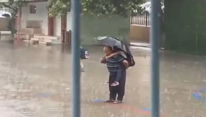 Dede torununu sırtına alarak yağmur altında İstiklal Marşı okudu